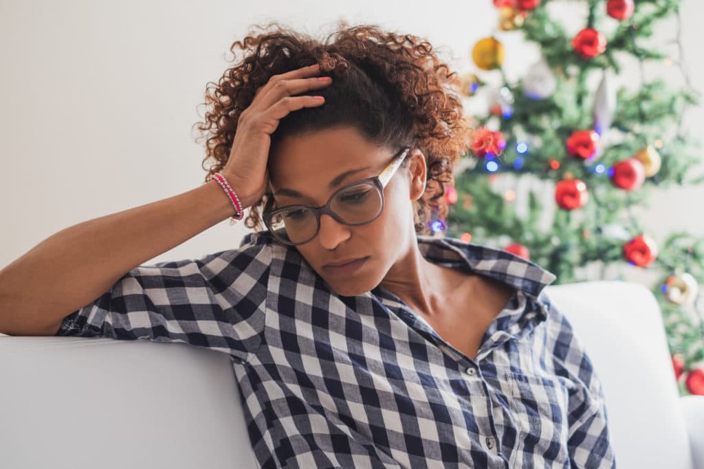 woman looking distressed with holiday tree in background